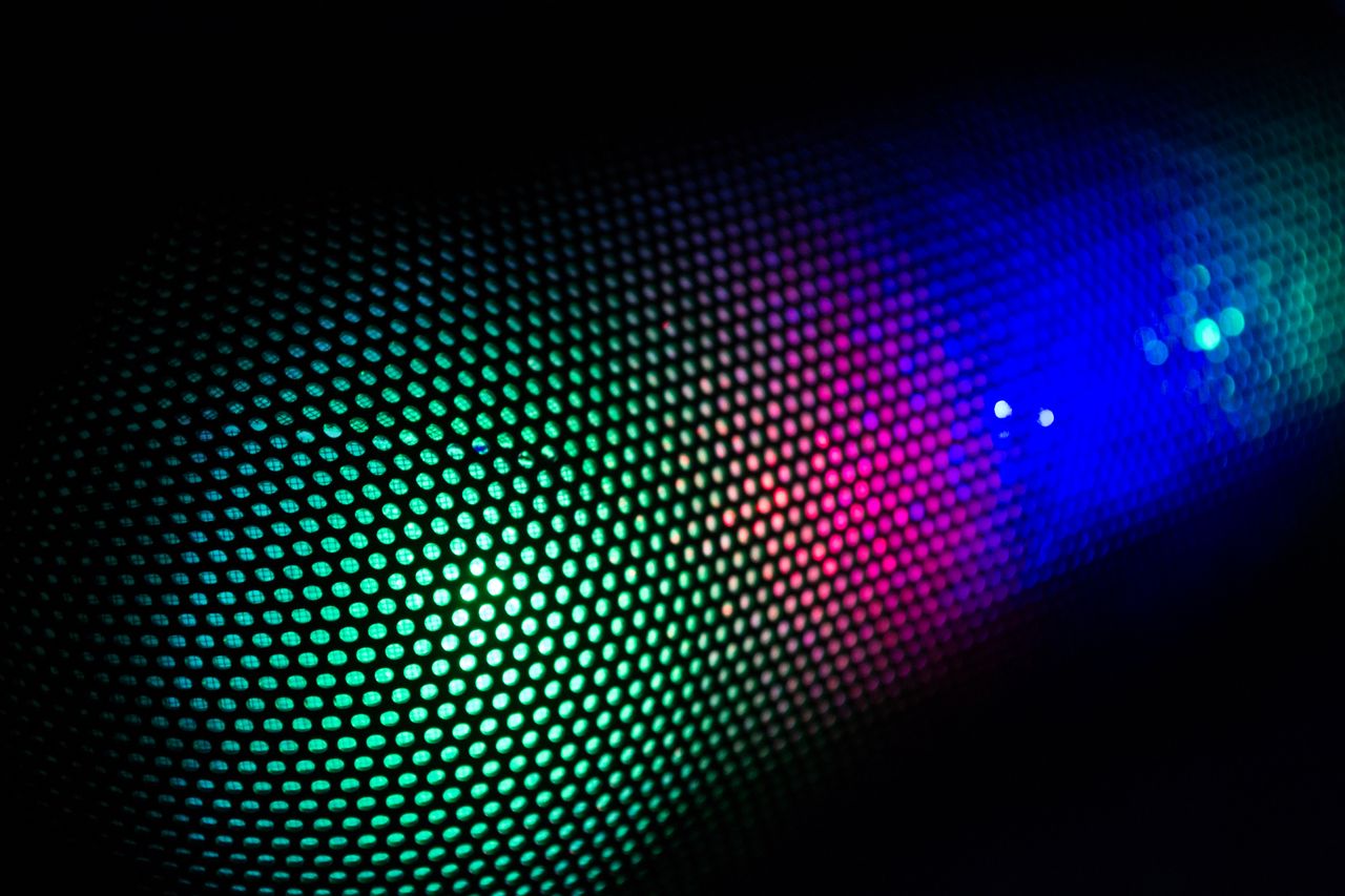 hero-img-02 Vivid abstract image of colorful LED lights through a speaker grille, showcasing vibrant technology design.