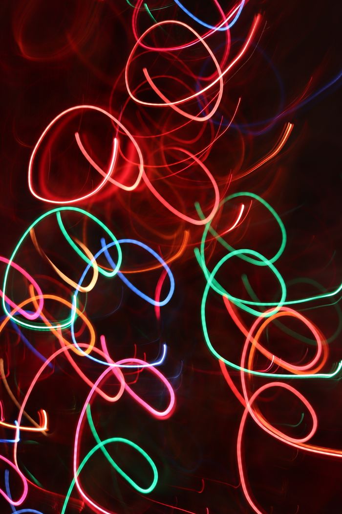 why-choose-us Dynamic long exposure shot of neon light trails creating colorful abstract patterns on a dark background.