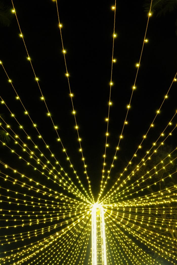 Yellow string lights radiate in a festive outdoor setup in Kolkata, India, casting a vibrant glow at night.
