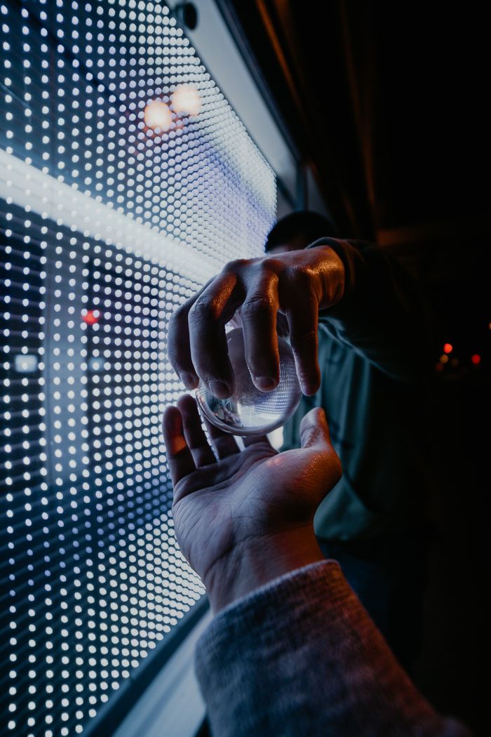 services-03 Hands exchanging a glass ball against a backdrop of neon lights, creating a futuristic ambiance.